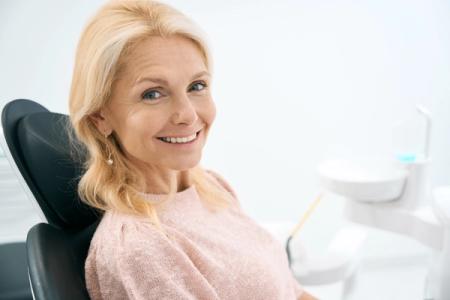 Smiling woman holding a clear dental aligner.